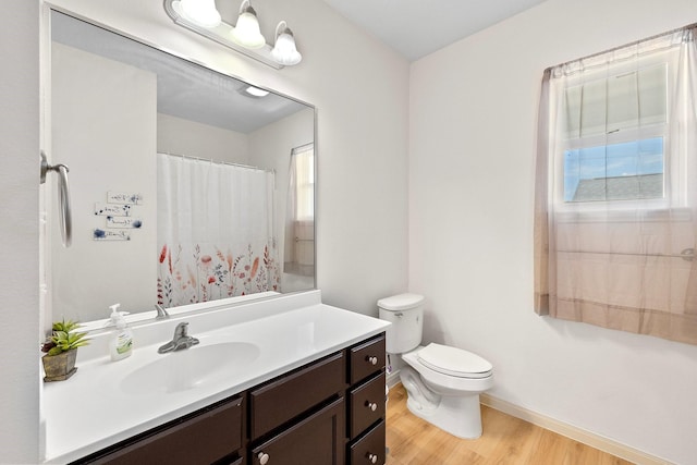 2107 54th St, Galveston, TX 77551 - full bath with wood finished floors, baseboards, toilet, vanity, and healthy amount of natural light