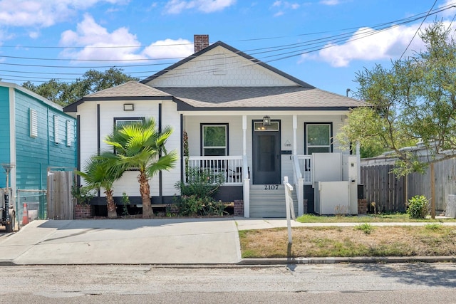 2107 54th St, Galveston, TX 77551 - shotgun-style home with covered porch, a chimney, roof with shingles, and fence