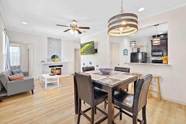 2107 54th St, Galveston, TX 77551 - dining space featuring light wood-style floors, crown molding, a ceiling fan, a stone fireplace, and recessed lighting