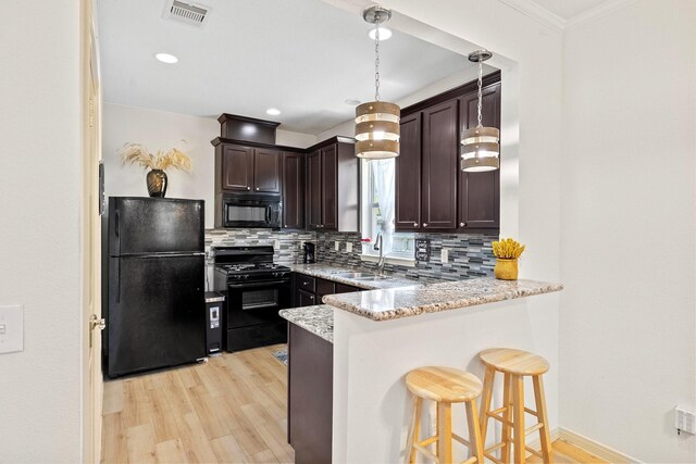 2107 54th St, Galveston, TX 77551 - kitchen featuring black appliances, a sink, light wood-type flooring, decorative backsplash, and dark brown cabinetry
