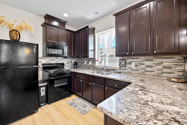 2107 54th St, Galveston, TX 77551 - kitchen featuring black appliances, a sink, light wood-style floors, dark brown cabinets, and backsplash