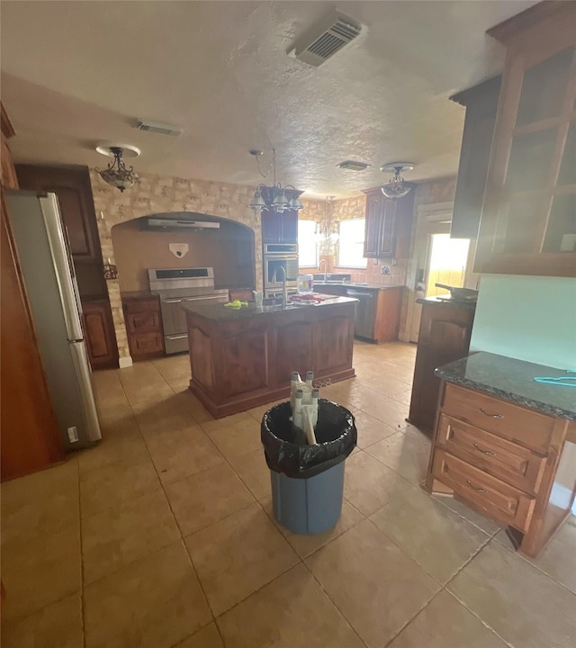 3811 Empress Ln, Richmond, TX 77406 - kitchen featuring appliances with stainless steel finishes, light tile patterned flooring, a kitchen island with sink, and a sink