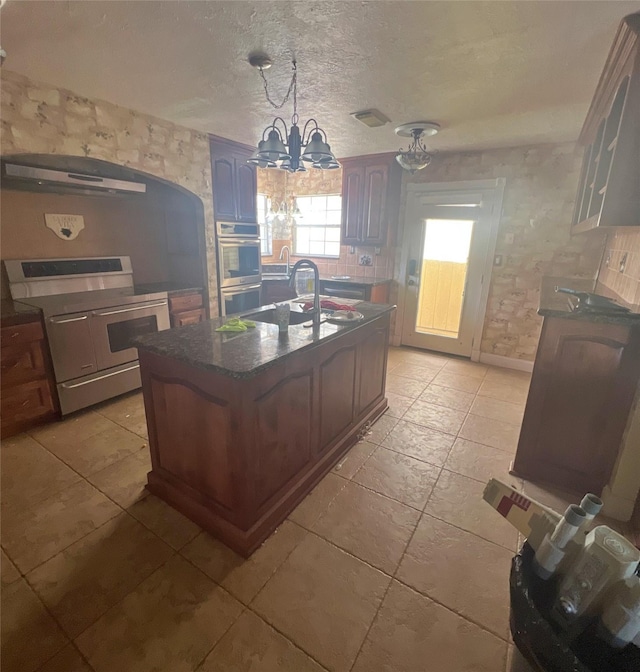 3811 Empress Ln, Richmond, TX 77406 - kitchen with appliances with stainless steel finishes, a chandelier, a sink, glass insert cabinets, and a center island with sink