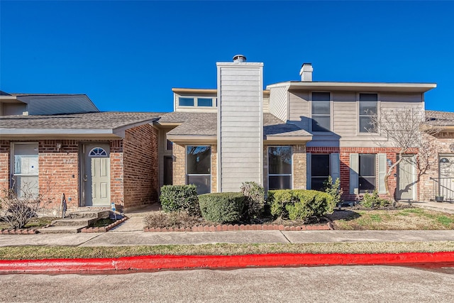 9393 Westwood Village Dr Unit 64, Houston, TX 77036 - view of front of house featuring brick siding, a chimney, and a shingled roof