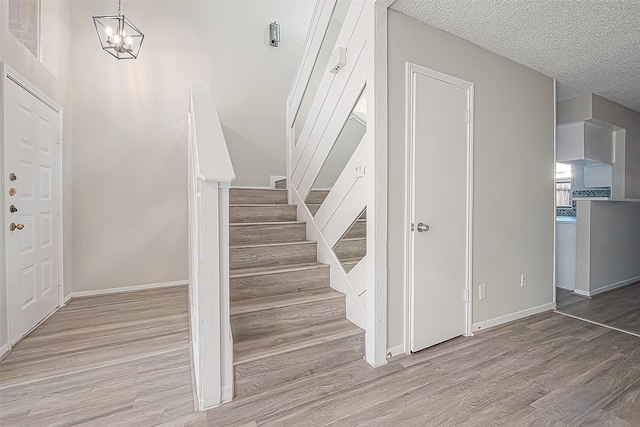9393 Westwood Village Dr Unit 64, Houston, TX 77036 - stairs with wood finished floors, a chandelier, baseboards, and a textured ceiling