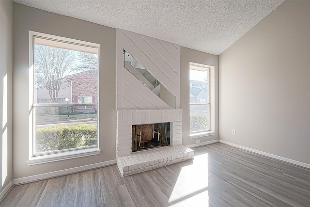 9393 Westwood Village Dr Unit 64, Houston, TX 77036 - unfurnished living room with wood finished floors, plenty of natural light, a textured ceiling, and a brick fireplace