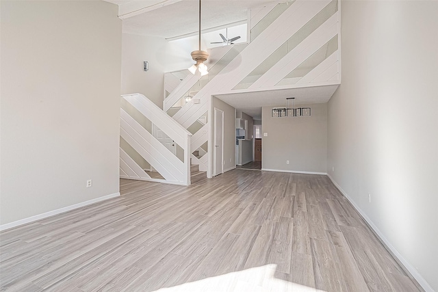 9393 Westwood Village Dr Unit 64, Houston, TX 77036 - unfurnished living room featuring light wood finished floors, ceiling fan, baseboards, stairs, and a high ceiling