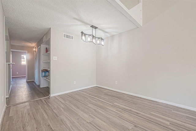 9393 Westwood Village Dr Unit 64, Houston, TX 77036 - unfurnished dining area with light wood-type flooring, baseboards, a textured ceiling, and a chandelier