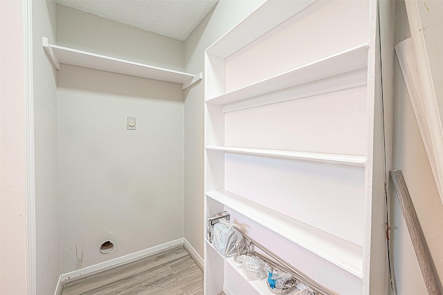 9393 Westwood Village Dr Unit 64, Houston, TX 77036 - laundry area with hookup for an electric dryer, light wood-style floors, a textured ceiling, and baseboards