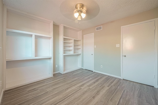 9393 Westwood Village Dr Unit 64, Houston, TX 77036 - unfurnished bedroom with wood finished floors, a textured ceiling, baseboards, a closet, and a ceiling fan