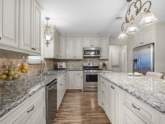 316 N Magnolia St, Highlands, TX 77562 - kitchen with appliances with stainless steel finishes, a sink, wood finished floors, and light stone counters