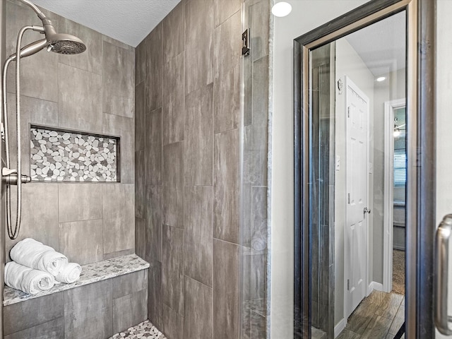 316 N Magnolia St, Highlands, TX 77562 - bathroom with tiled shower, a textured ceiling, and wood finished floors
