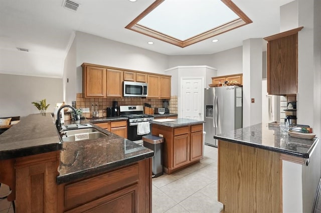 3522 Plymouth Pointe Ln, Missouri City, TX 77459 - kitchen featuring appliances with stainless steel finishes, a sink, a peninsula, backsplash, and brown cabinetry