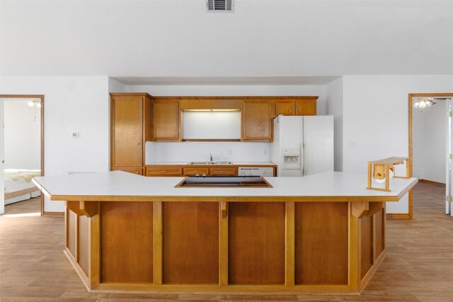 908 W Ln, Crystal Beach, TX 77650 - kitchen featuring white refrigerator with ice dispenser, light countertops, black electric stovetop, light wood-style floors, and brown cabinetry
