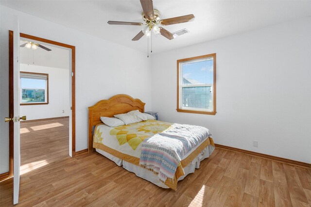 908 W Ln, Crystal Beach, TX 77650 - bedroom featuring multiple windows, light wood-type flooring, and baseboards