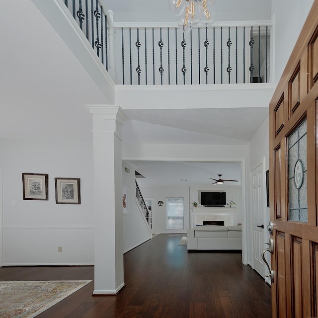 foyer featuring stairs, dark wood-style floors, a chandelier, ceiling fan, and a towering ceiling