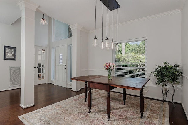 dining space with decorative columns, wood finished floors, baseboards, and crown molding