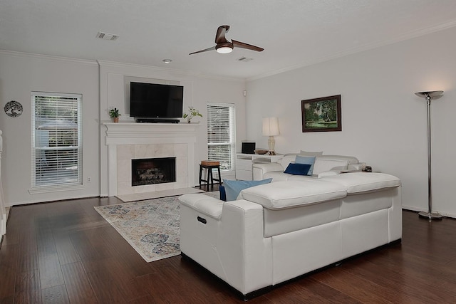 living room with ceiling fan, dark wood-style floors, crown molding, and a tiled fireplace