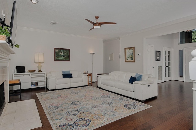living area with ceiling fan, ornamental molding, dark wood finished floors, and a fireplace with flush hearth