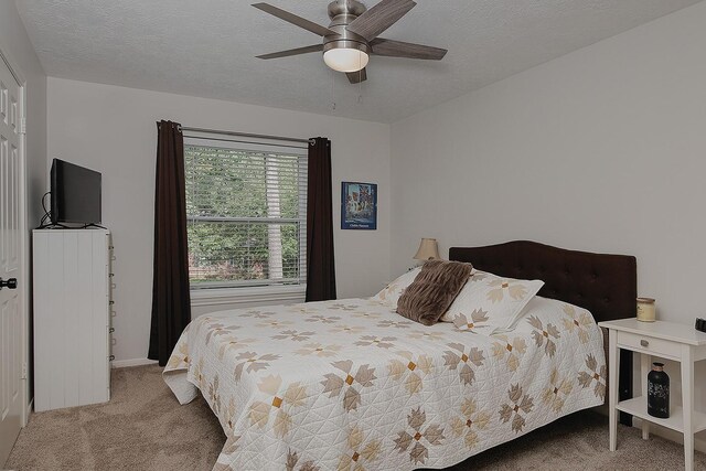 carpeted bedroom featuring a textured ceiling, ceiling fan, and baseboards