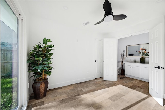 bedroom featuring light wood-style floors, baseboards, a ceiling fan, and a sink