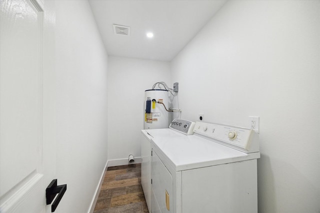 clothes washing area featuring washing machine and dryer, electric water heater, dark wood-style flooring, and baseboards