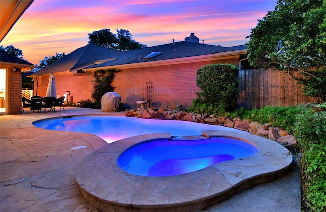 13702 Senca Park Dr, Houston, TX 77077 - pool at dusk with an in-ground hot tub, a patio, and fence