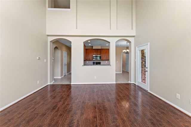 12314 Shore Lands Rd, Cypress, TX 77433 - unfurnished living room featuring a high ceiling, wood finished floors, a chandelier, baseboards, and arched walkways
