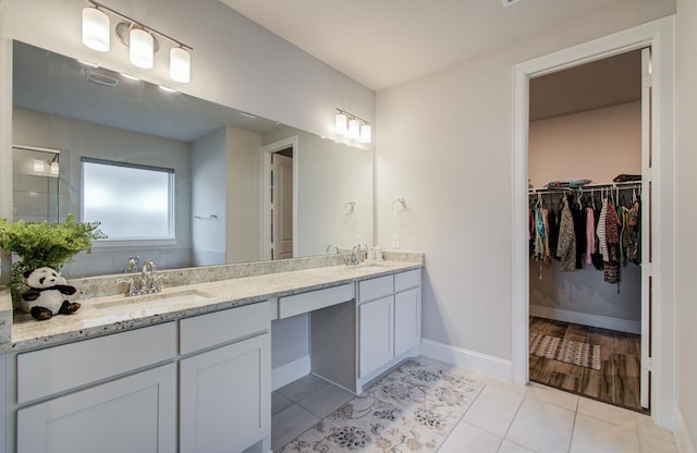 10014 Knollwood Ln, Missouri City, TX 77459 - full bathroom featuring tile patterned floors, double vanity, a walk in closet, and baseboards
