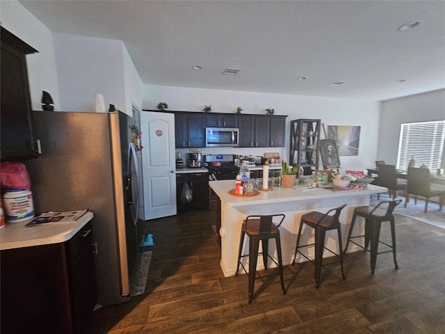 21303 Riverdew Dr, Katy, TX 77449 - kitchen with appliances with stainless steel finishes, a breakfast bar, light countertops, a kitchen island with sink, and recessed lighting