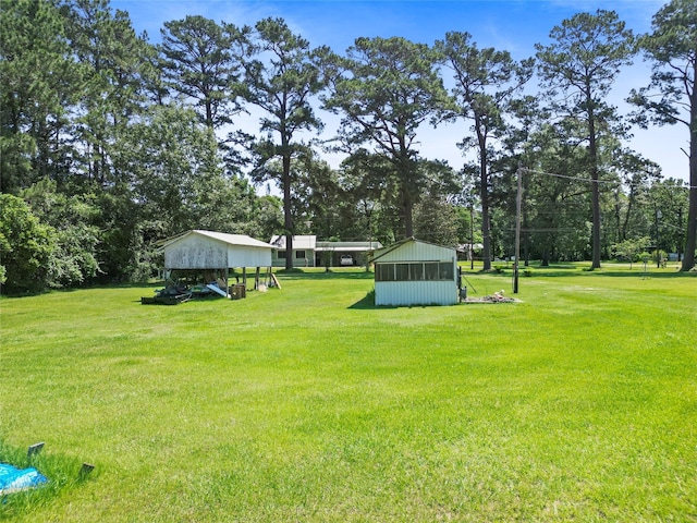135 Sweetgum St, Trinity, TX 75862 - view of grassy yard featuring an outbuilding, a carport, view of scattered trees, and a storage shed
