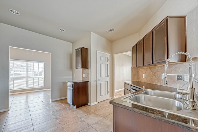 5006 Forest Hurst Gln, Spring, TX 77373 - kitchen featuring light tile patterned floors, a sink, dark countertops, tasteful backsplash, and baseboards