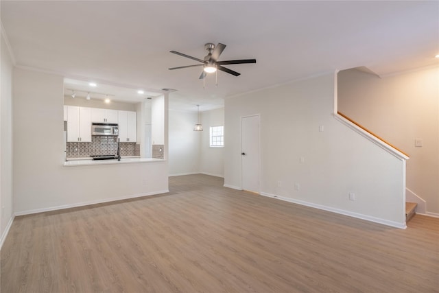 9850 Pagewood Ln Unit 909, Houston, TX 77042 - unfurnished living room with a ceiling fan, light wood-style floors, stairs, baseboards, and crown molding