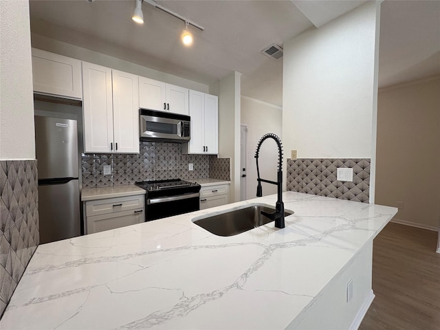 9850 Pagewood Ln Unit 909, Houston, TX 77042 - kitchen with appliances with stainless steel finishes, a sink, light stone countertops, wood finished floors, and white cabinets