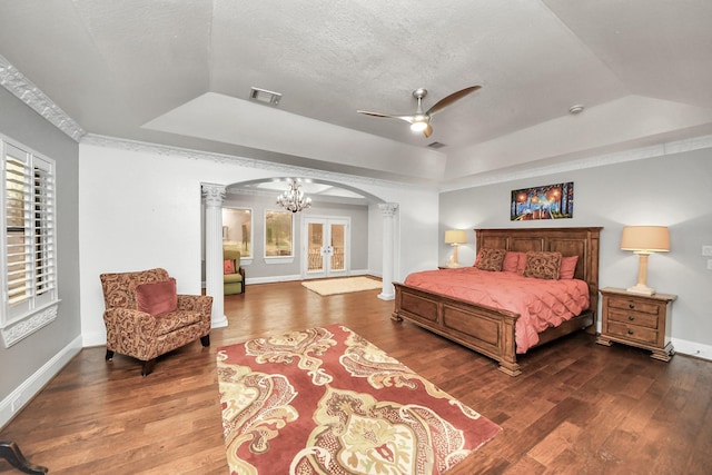 11503 Renaissance Dr, Montgomery, TX 77356 - bedroom featuring ornate columns, a tray ceiling, arched walkways, wood finished floors, and a textured ceiling