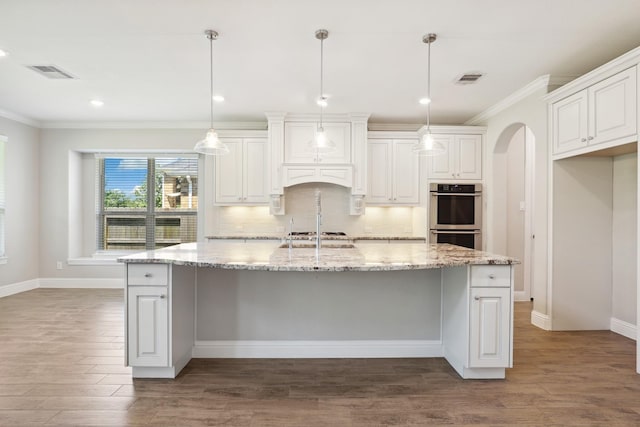 29407 Amber Meadows Ct, Katy, TX 77494 - kitchen with stainless steel double oven, crown molding, dark wood finished floors, arched walkways, and white cabinetry
