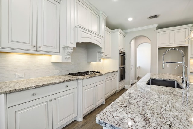 29407 Amber Meadows Ct, Katy, TX 77494 - kitchen featuring a sink, appliances with stainless steel finishes, ornamental molding, white cabinets, and arched walkways