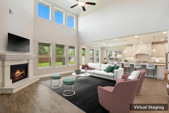 29407 Amber Meadows Ct, Katy, TX 77494 - living area with ornamental molding, light wood finished floors, a premium fireplace, ceiling fan, and a towering ceiling