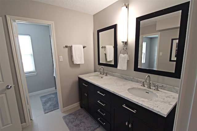 full bathroom featuring double vanity, a textured ceiling, baseboards, and tile patterned flooring