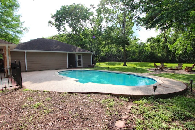 swimming pool with an outdoor fire pit, a patio area, a lawn, and view of wooded area