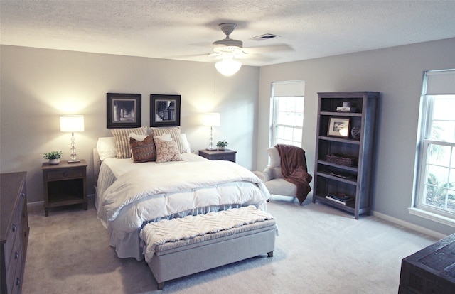 bedroom with light colored carpet, baseboards, a textured ceiling, and ceiling fan