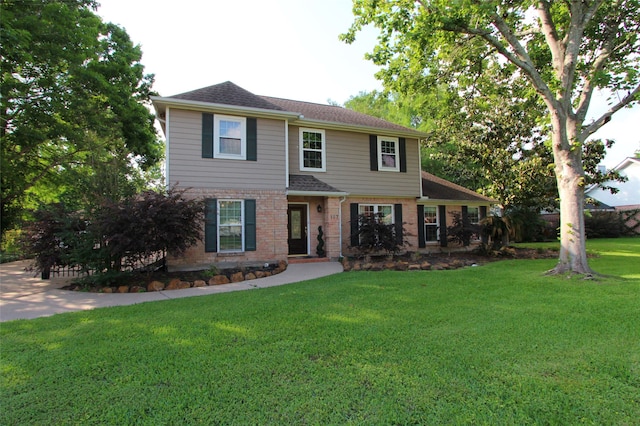 view of front of house featuring a front yard, brick siding, and a shingled roof