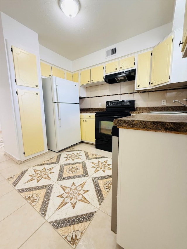 6405 Westward St Unit 96, Houston, TX 77081 - kitchen with freestanding refrigerator, black / electric stove, under cabinet range hood, dark countertops, and light tile patterned floors