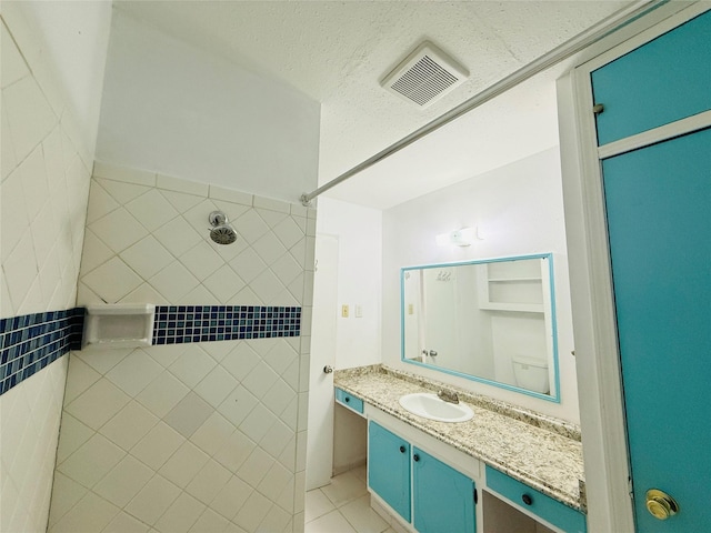 6405 Westward St Unit 96, Houston, TX 77081 - bathroom featuring a tile shower, vanity, tile patterned floors, and a textured ceiling