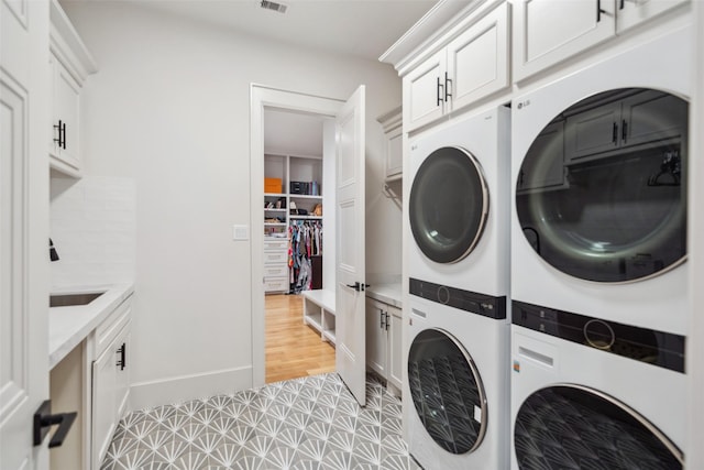 1221 Lamonte Ln, Houston, TX 77018 - laundry room featuring stacked washer and clothes dryer, cabinet space, and baseboards