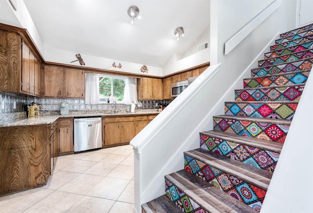 22331 Unicorns Horn Ln, Katy, TX 77449 - kitchen with stainless steel appliances, brown cabinetry, decorative backsplash, lofted ceiling, and light countertops
