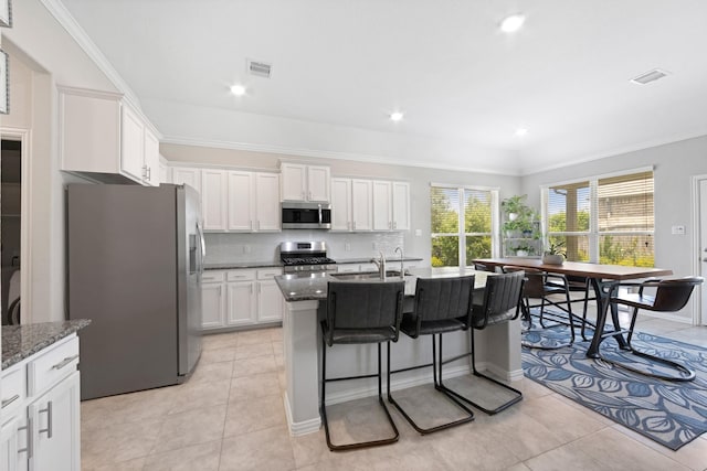 16114 Lake Amistad Pl, Cypress, TX 77433 - kitchen with stainless steel appliances, light tile patterned flooring, white cabinets, a kitchen breakfast bar, and tasteful backsplash