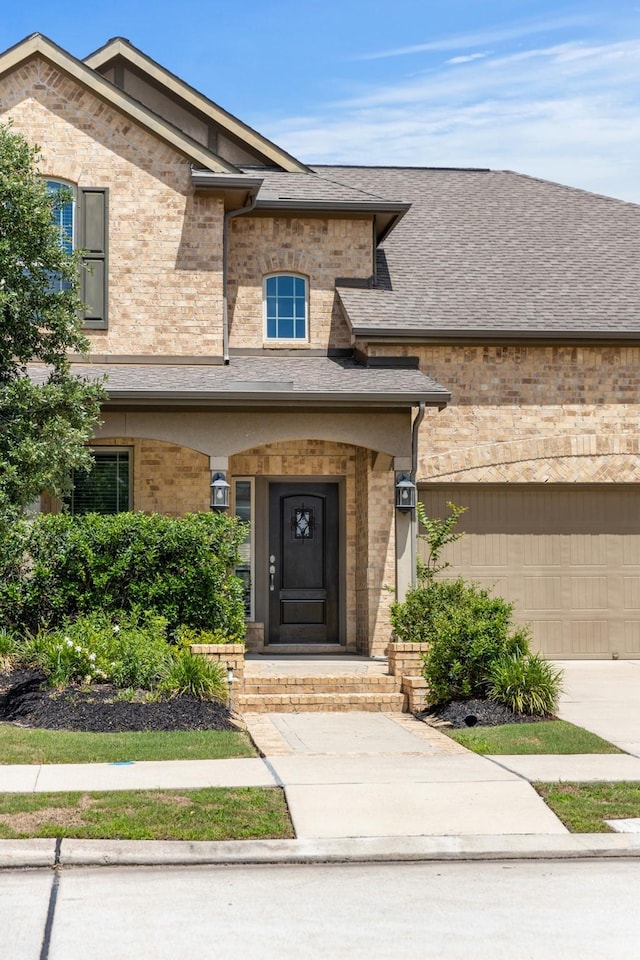 16114 Lake Amistad Pl, Cypress, TX 77433 - view of exterior entry featuring brick siding, a shingled roof, and driveway