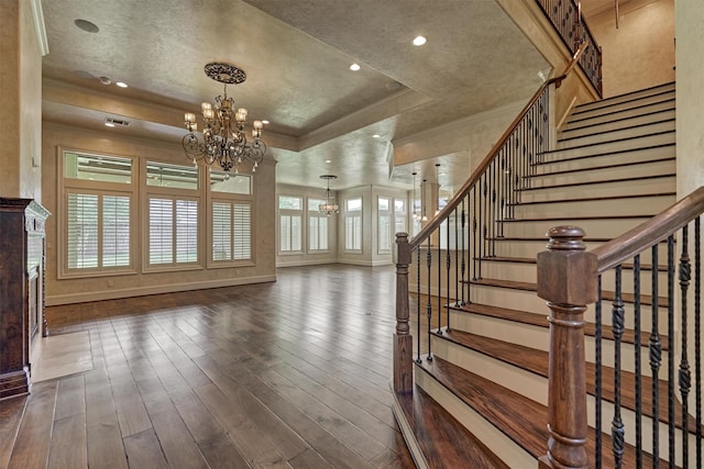 61 Parkgate, Shenandoah, TX 77381 - unfurnished living room featuring a chandelier, a raised ceiling, dark wood-style flooring, stairway, and crown molding