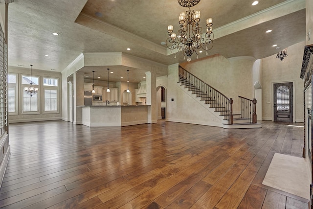 61 Parkgate, Shenandoah, TX 77381 - unfurnished living room with a chandelier, arched walkways, stairway, dark wood-style floors, and a tray ceiling